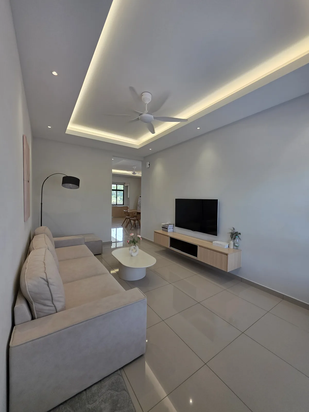 Ruang tamu unit contoh STI Amanria dengan sofa dan kabinet TV
